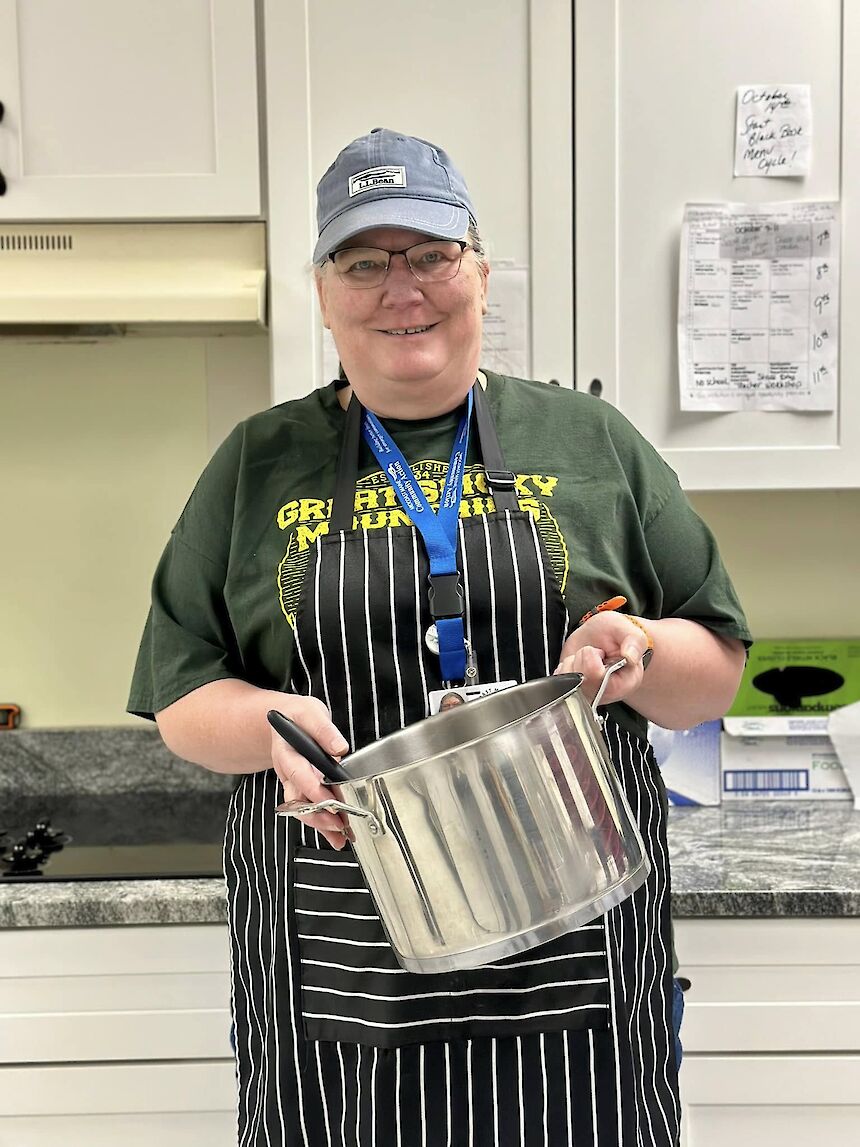 woman in a kitchen holding a large pot