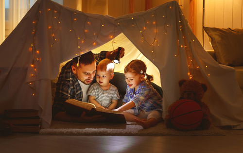 father and daughters in tent reading